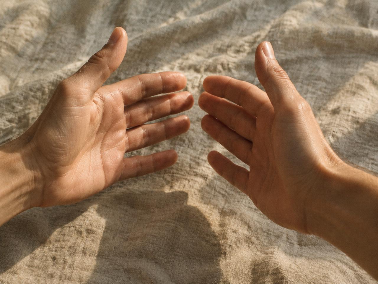 Deux mains ouvertes, paumes face à face, au-dessus d'un tissu en lin